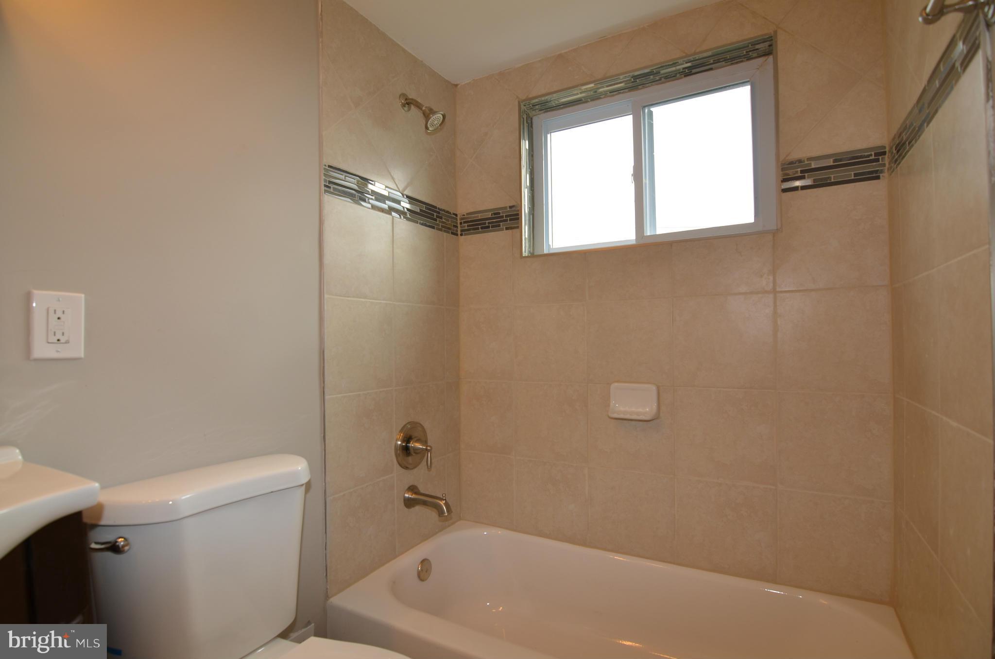 8254 Kavanagh Road Baltimore, MD 21222 - Photo 16 of 20 a bathroom with a bathtub a window and a shower