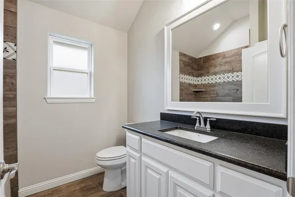 a bathroom with a granite countertop toilet sink and mirror