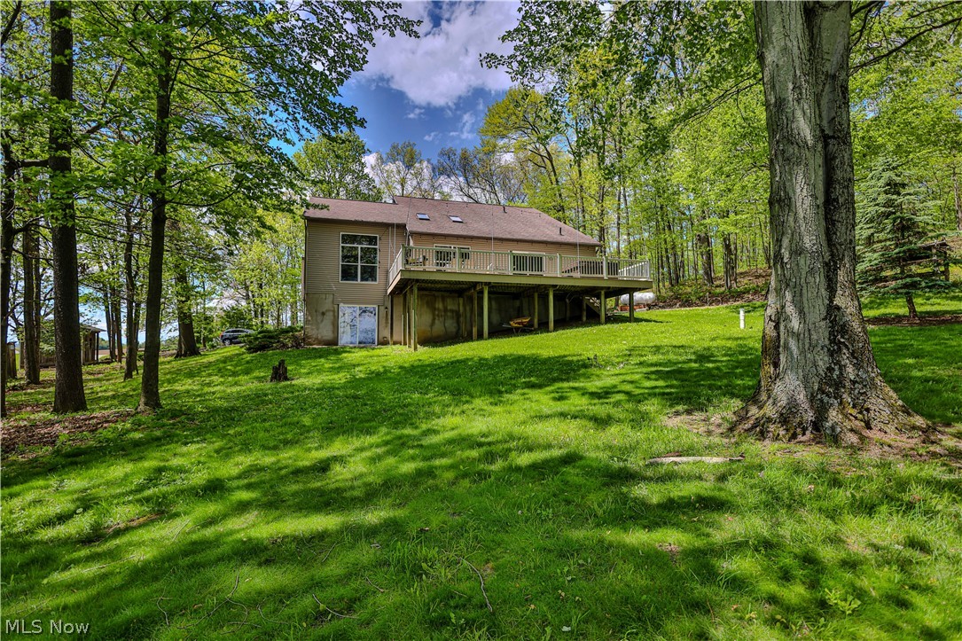 11154 Johnsford Road Southwest Beach City, OH 44608 - Photo 4 of 50 Expansive grassy yard with mature trees surrounding a two-story residence featuring a large elevated deck