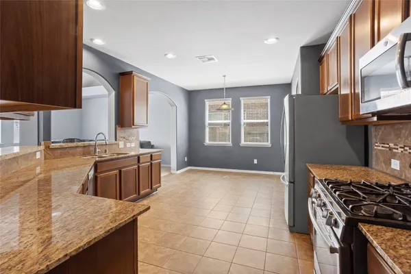 a kitchen with stainless steel appliances granite countertop a stove a sink and a microwave
