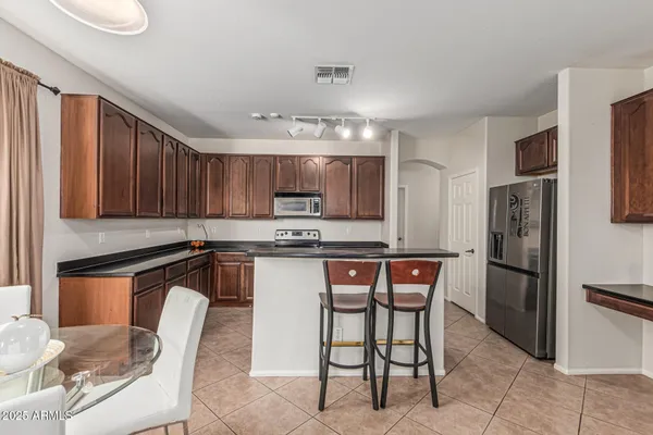 a kitchen with stainless steel appliances kitchen island granite countertop a refrigerator a stove top oven a sink and dishwasher