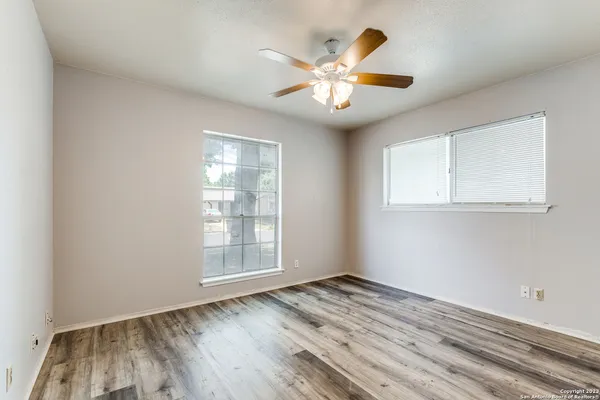 an empty room with wooden floor and windows