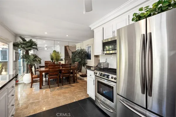 a kitchen with stainless steel appliances a refrigerator a stove a dining table and chairs with wooden floor