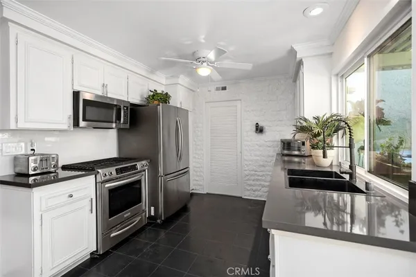 a kitchen with stainless steel appliances granite countertop a stove a sink dishwasher a refrigerator and a microwave oven with wooden floor