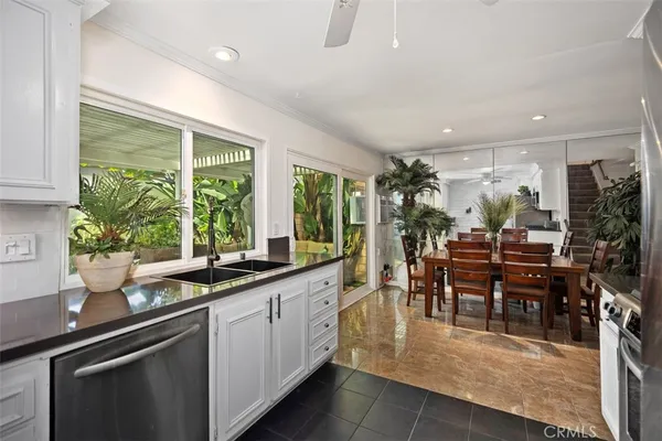 a dining hall with stainless steel appliances granite countertop a stove a sink a dining table and chairs with wooden floor