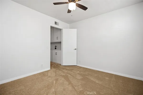 an empty room with a ceiling fan and carpet