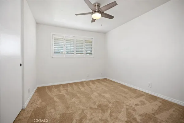 an empty room with a window and a fan