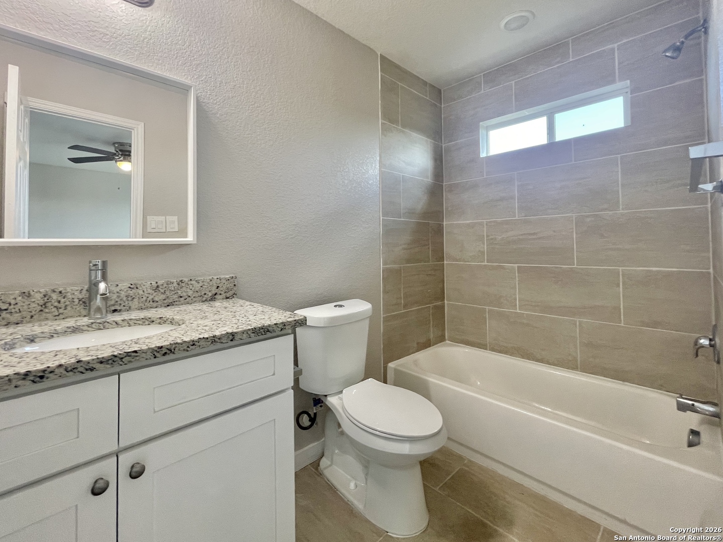 6938 Crestway Road, Unit 1 San Antonio, TX 78239 - Photo 14 of 16 a bathroom with a granite countertop toilet a sink and bathtub