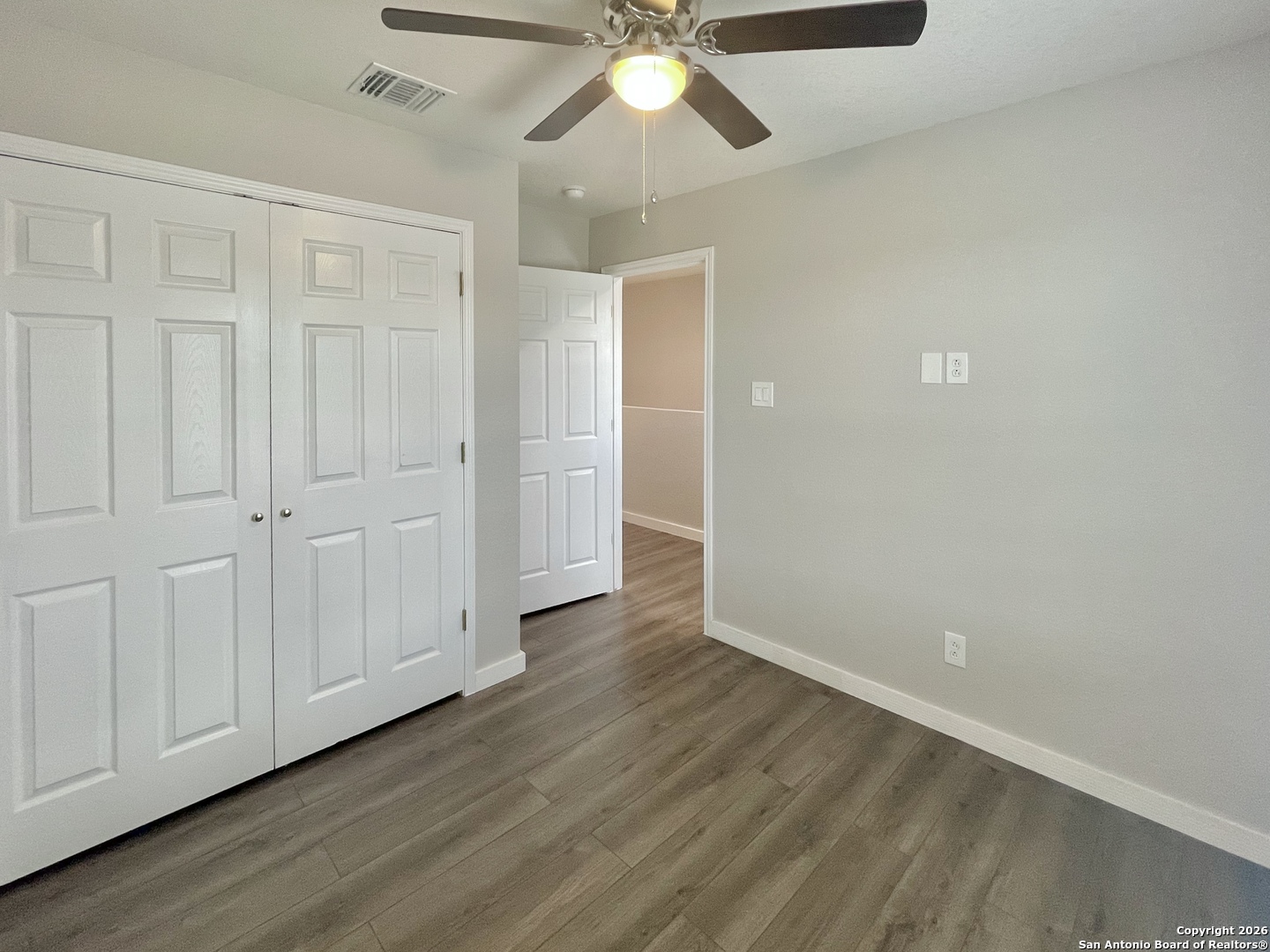 6938 Crestway Road, Unit 1 San Antonio, TX 78239 - Photo 15 of 16 an empty room with wooden floor ceiling fan and windows