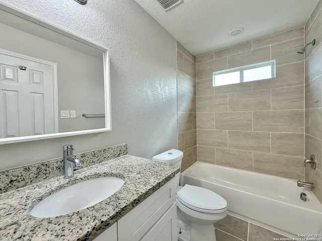 a bathroom with a granite countertop toilet a sink and a bathtub