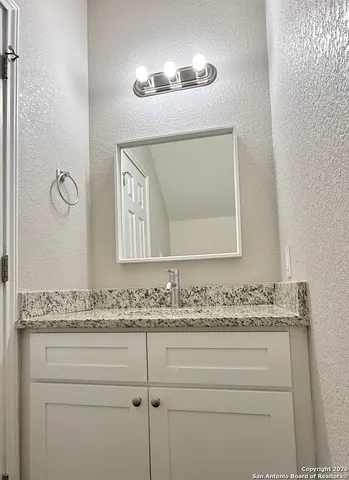 a bathroom with a granite countertop sink and a mirror