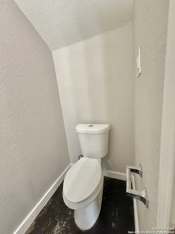 a white toilet sitting next to a white wall