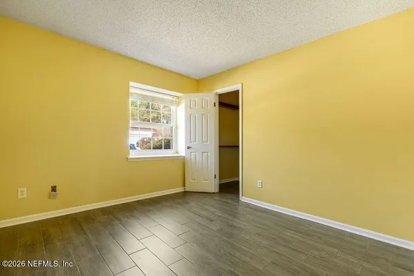 a view of an empty room with wooden floor and a window