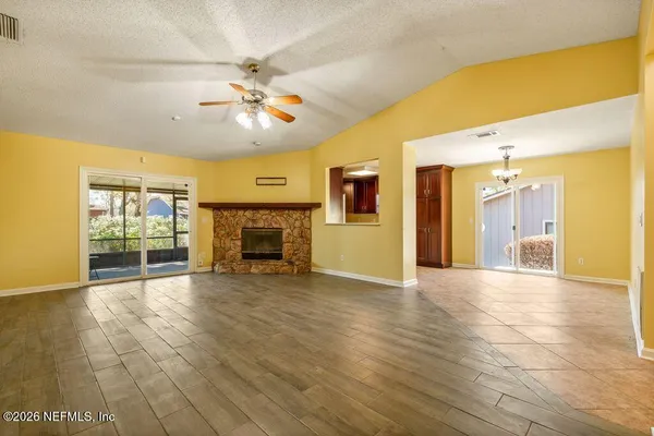 a view of an empty room with a fireplace and a chandelier fan
