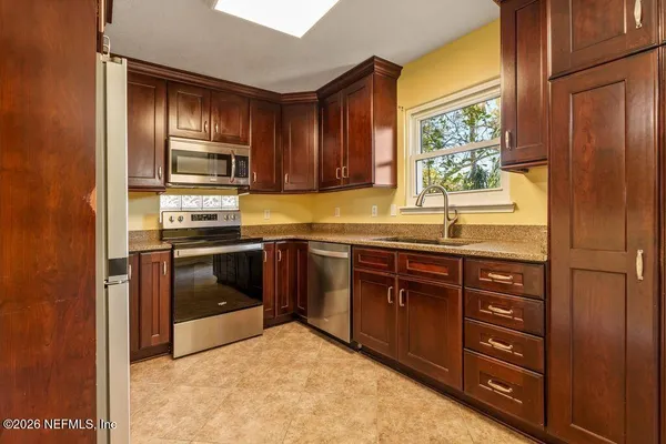 a kitchen with stainless steel appliances granite countertop a refrigerator and wooden cabinets