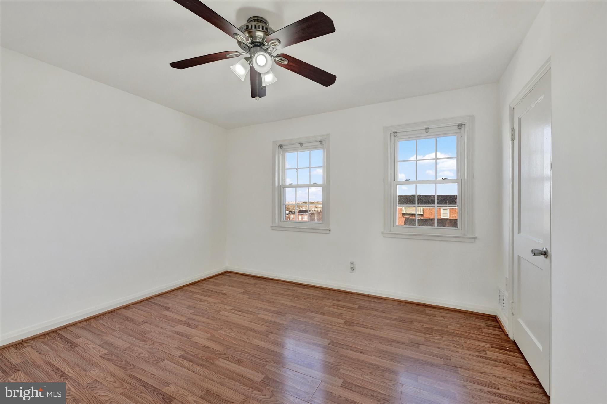 7007 Bank Street Baltimore, MD 21224 - Photo 11 of 18 an empty room with wooden floor ceiling fan and windows