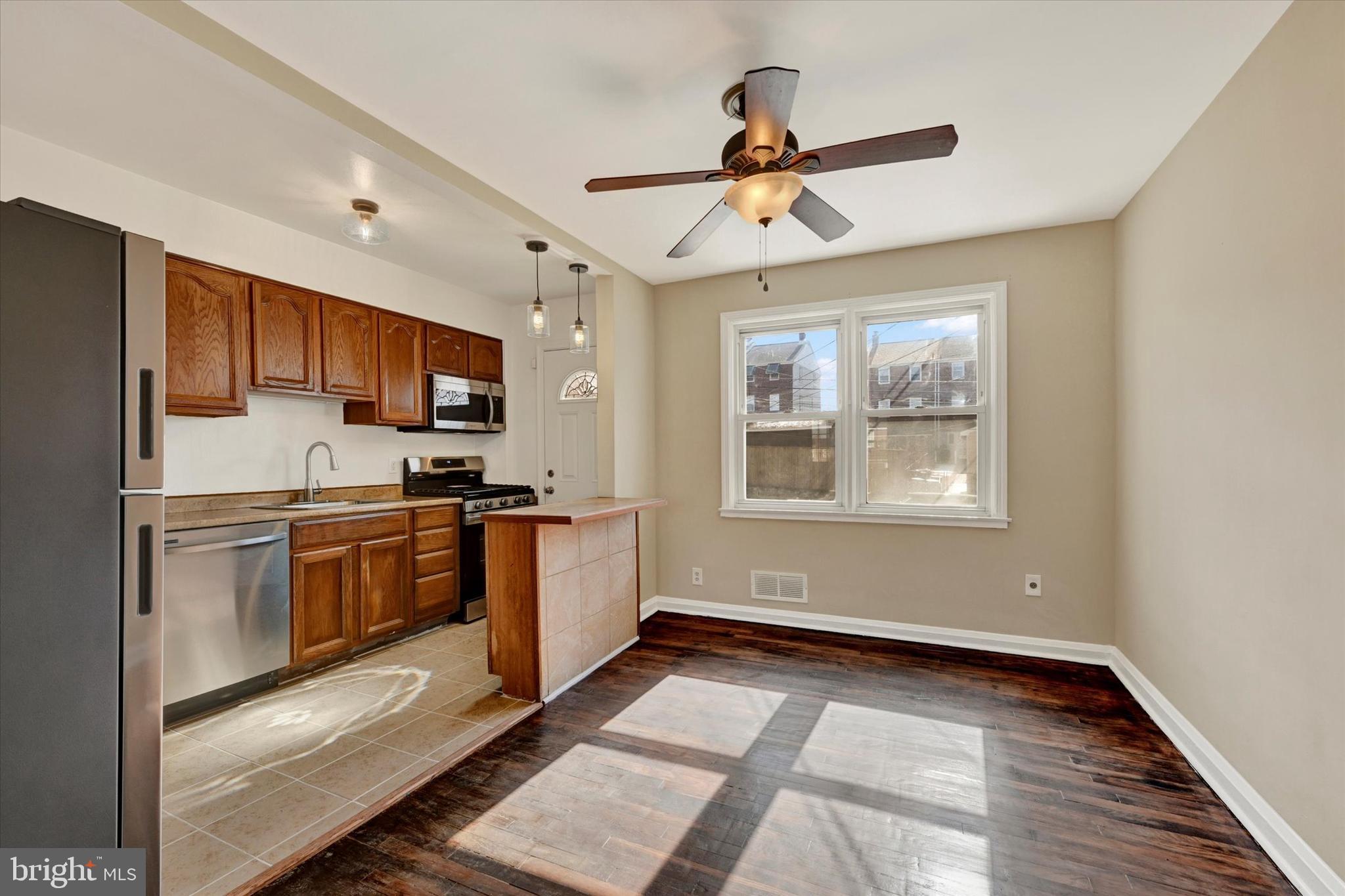 7007 Bank Street Baltimore, MD 21224 - Photo 5 of 18 a kitchen with granite countertop a refrigerator a sink dishwasher a stove and white cabinets with wooden floor