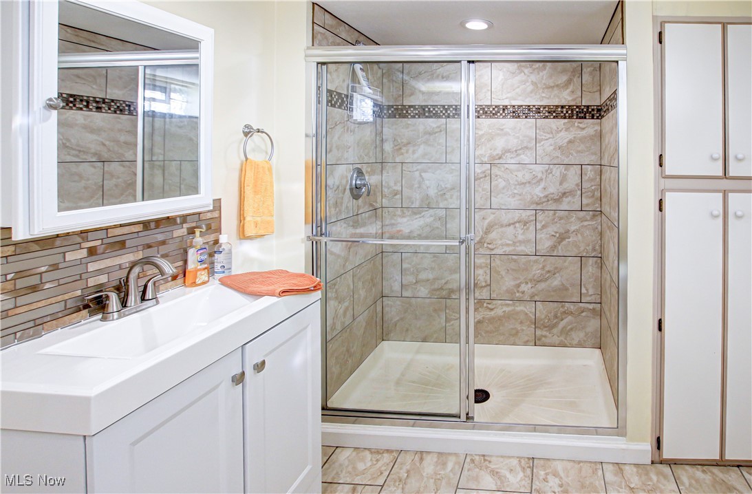 4234 Grafton Road Brunswick, OH 44212 - Photo 27 of 40 Bathroom featuring vanity, decorative backsplash, walk in shower, and tile patterned floors