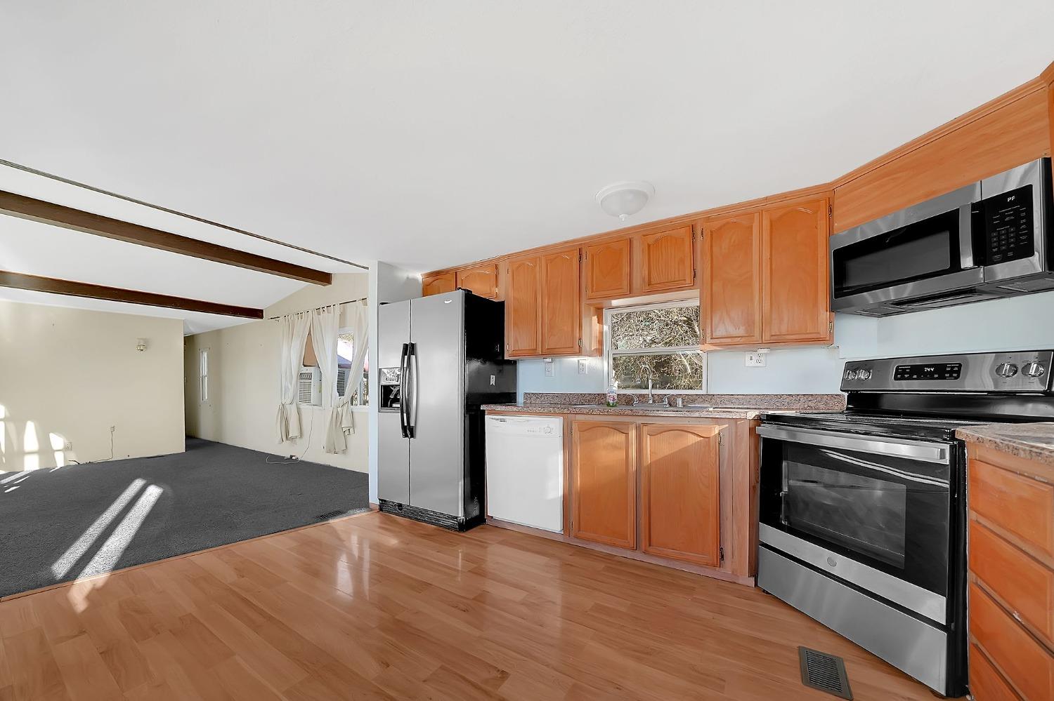 2000 Camanche Road, Unit 16 Ione, CA 95640 - Photo 13 of 36 a kitchen with stainless steel appliances granite countertop a stove top oven a refrigerator and white cabinets with wooden floor