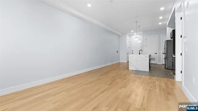 a view of a room with wooden floor and a refrigerator