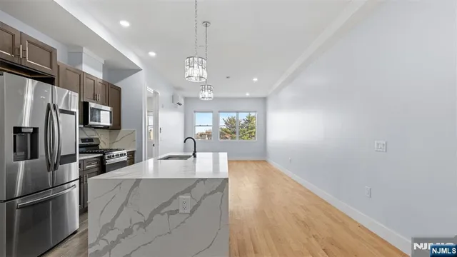 a large kitchen with stainless steel appliances a large counter top and a refrigerator