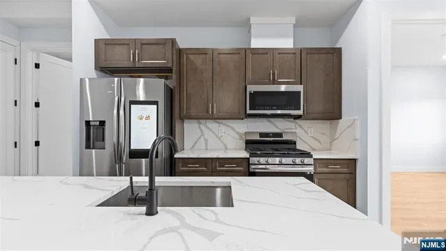 a kitchen with granite countertop a refrigerator and a stove top oven