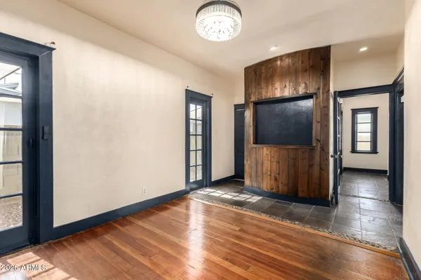 an empty room with wooden floor mirror and windows