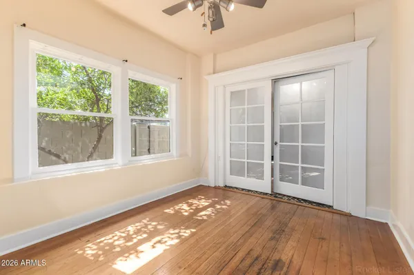 an empty room with wooden floor cabinet and windows