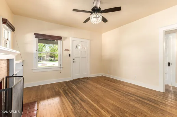 a view of empty room with wooden floor and fan