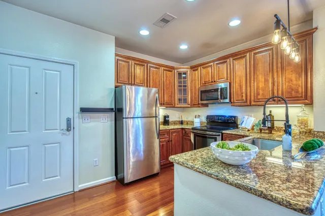 a kitchen with stainless steel appliances granite countertop a refrigerator a stove top oven a sink and dishwasher