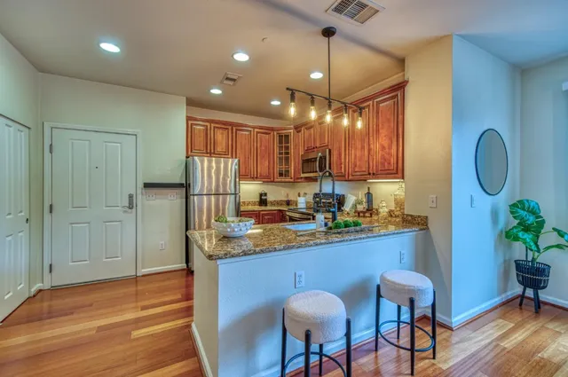 a kitchen with stainless steel appliances granite countertop a sink refrigerator dining table and chairs