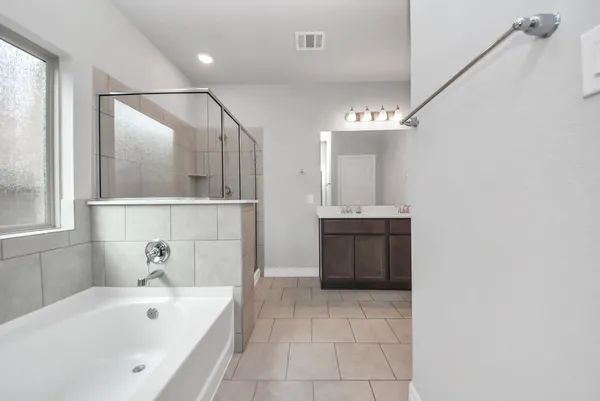 a bathroom with a tub a sink and mirror