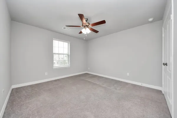 an empty room with windows and fan