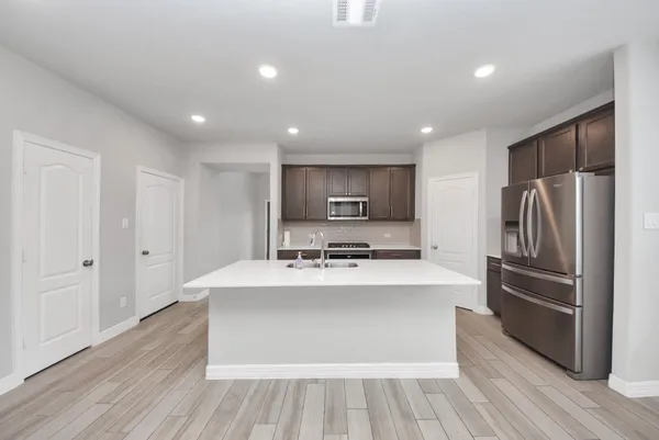 a large white kitchen with wooden floors stainless steel appliances and cabinets