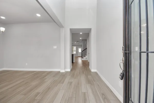 a view of a hallway with wooden floor and a bathroom