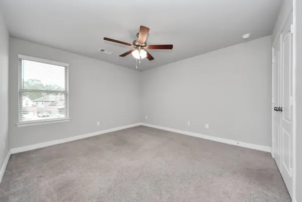 an empty room with a window and a fan