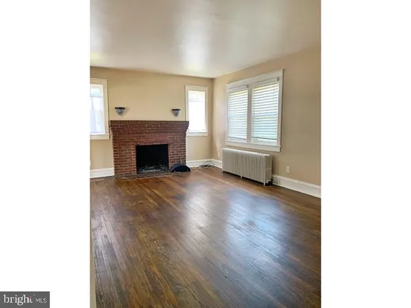 a view of empty room with fireplace and wooden floor