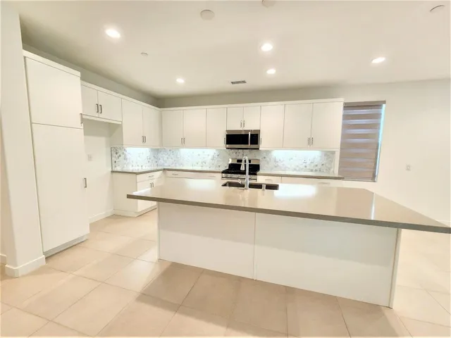 a kitchen with stainless steel appliances granite countertop a sink a stove a refrigerator a microwave and cabinets