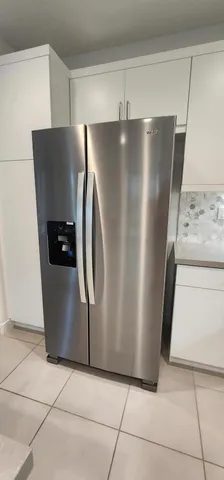 a view of a refrigerator in kitchen and an empty room