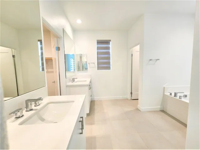 a spacious bathroom with a tub sink and mirror