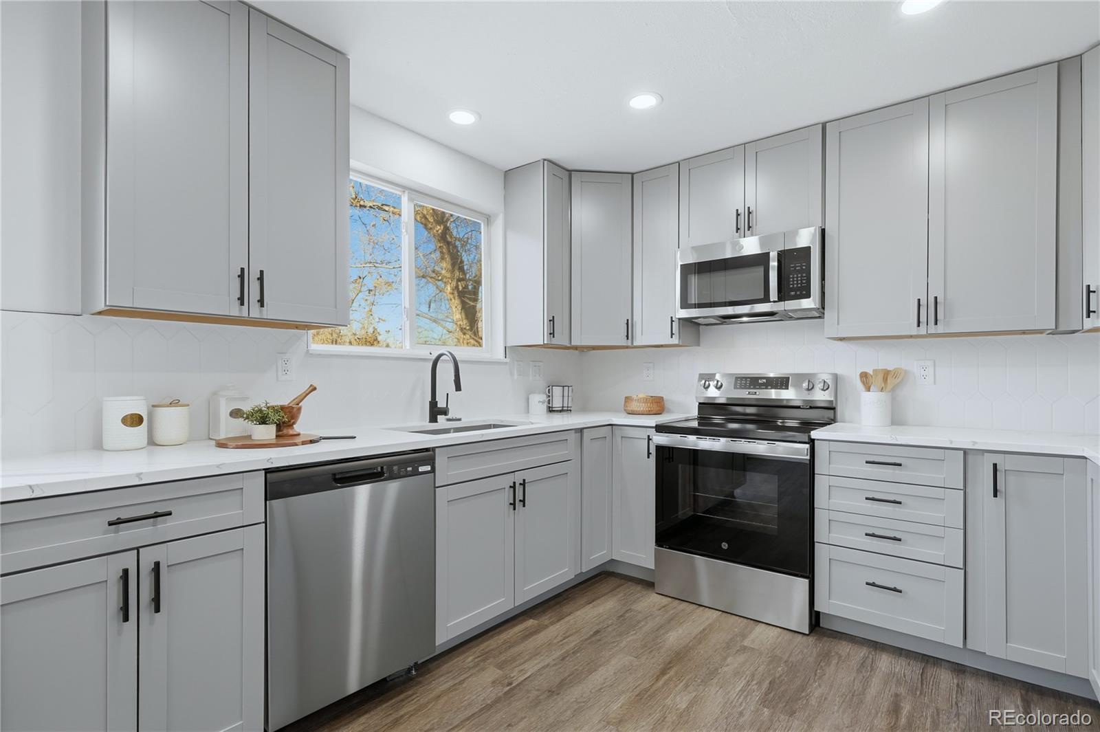 3173 South Nucla Street Aurora, CO 80013 - Photo 9 of 34 a kitchen with stainless steel appliances granite countertop a sink and cabinets with wooden floors