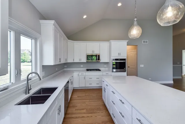 a large kitchen with stainless steel appliances kitchen island a large counter space a sink a window and cabinets