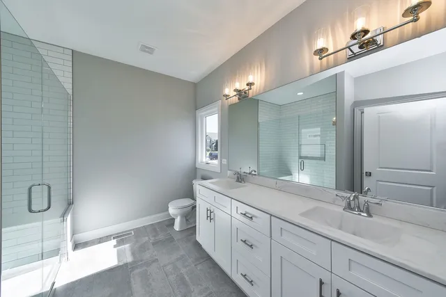 a bathroom with a double vanity sink and mirror with toilet