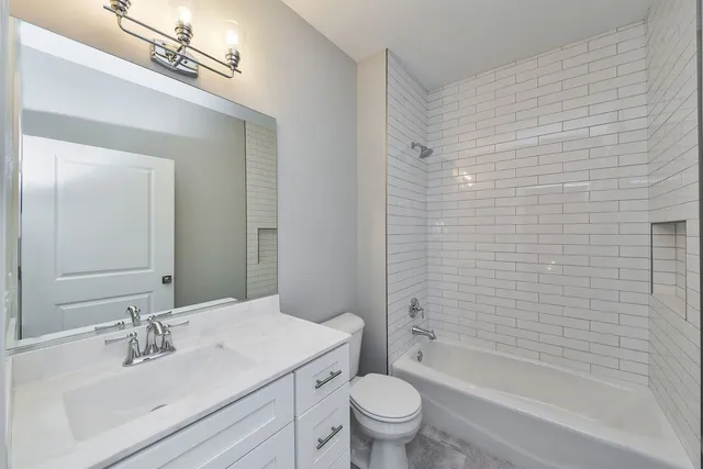 a bathroom with a bathtub shower sink vanity mirror and toilet