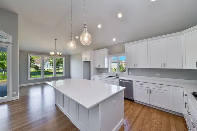 a kitchen with kitchen island granite countertop a stove a sink a center island and wooden floor