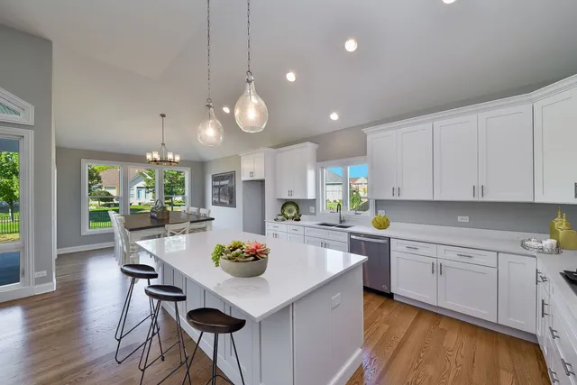 a kitchen with a dining table chairs and white cabinets
