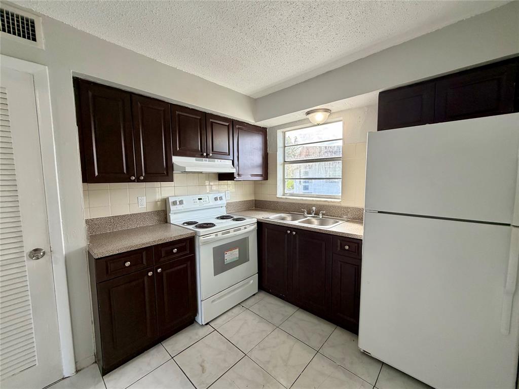 874 Southwest 10th Drive, Unit 741216 Pompano Beach, FL 33060 - Photo 7 of 16 a kitchen with granite countertop a refrigerator stove top oven and sink