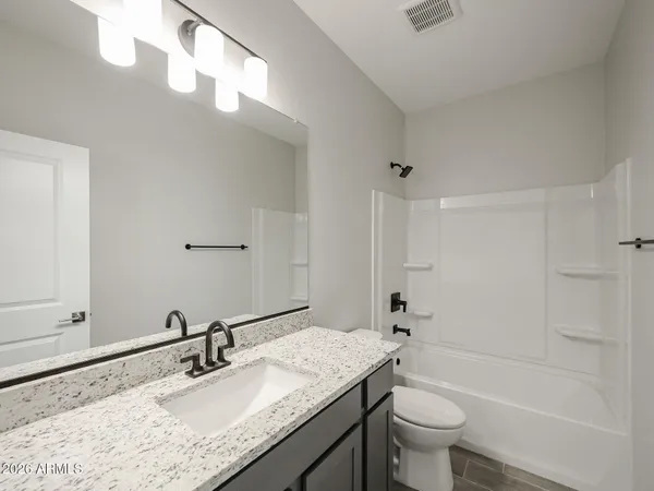 a bathroom with a granite countertop sink a toilet and shower