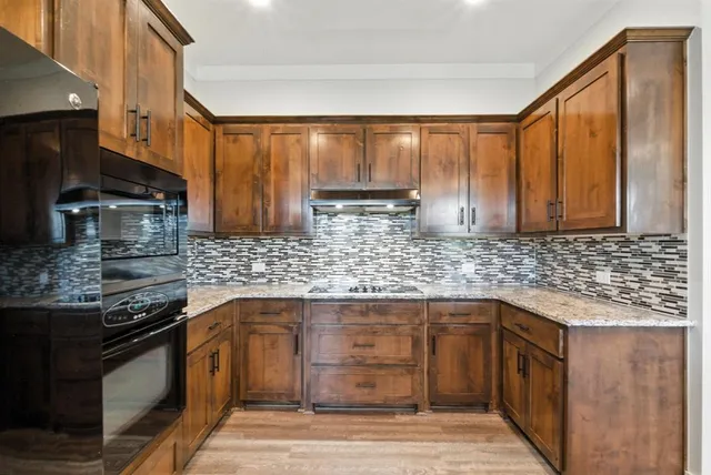 a kitchen with stainless steel appliances granite countertop wooden cabinets and a stove top oven