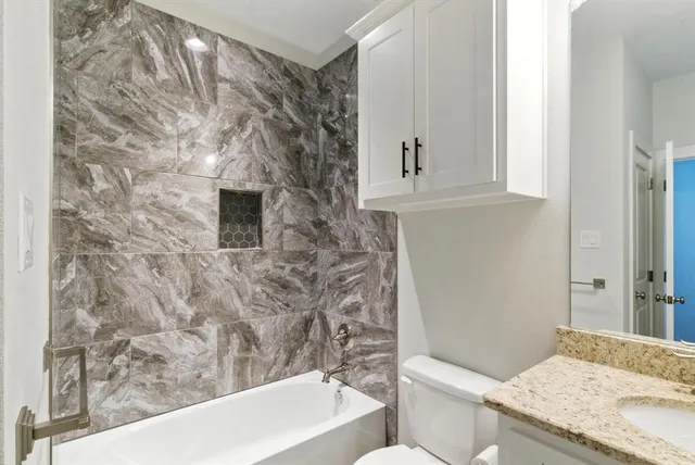 a bathroom with a granite countertop sink a toilet and bathtub
